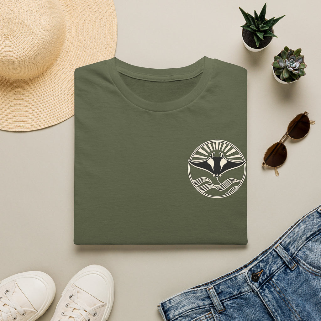 Folded military green t-shirt showing the small manta ray sunrise badge on the chest, flat lay with sunglasses and jeans