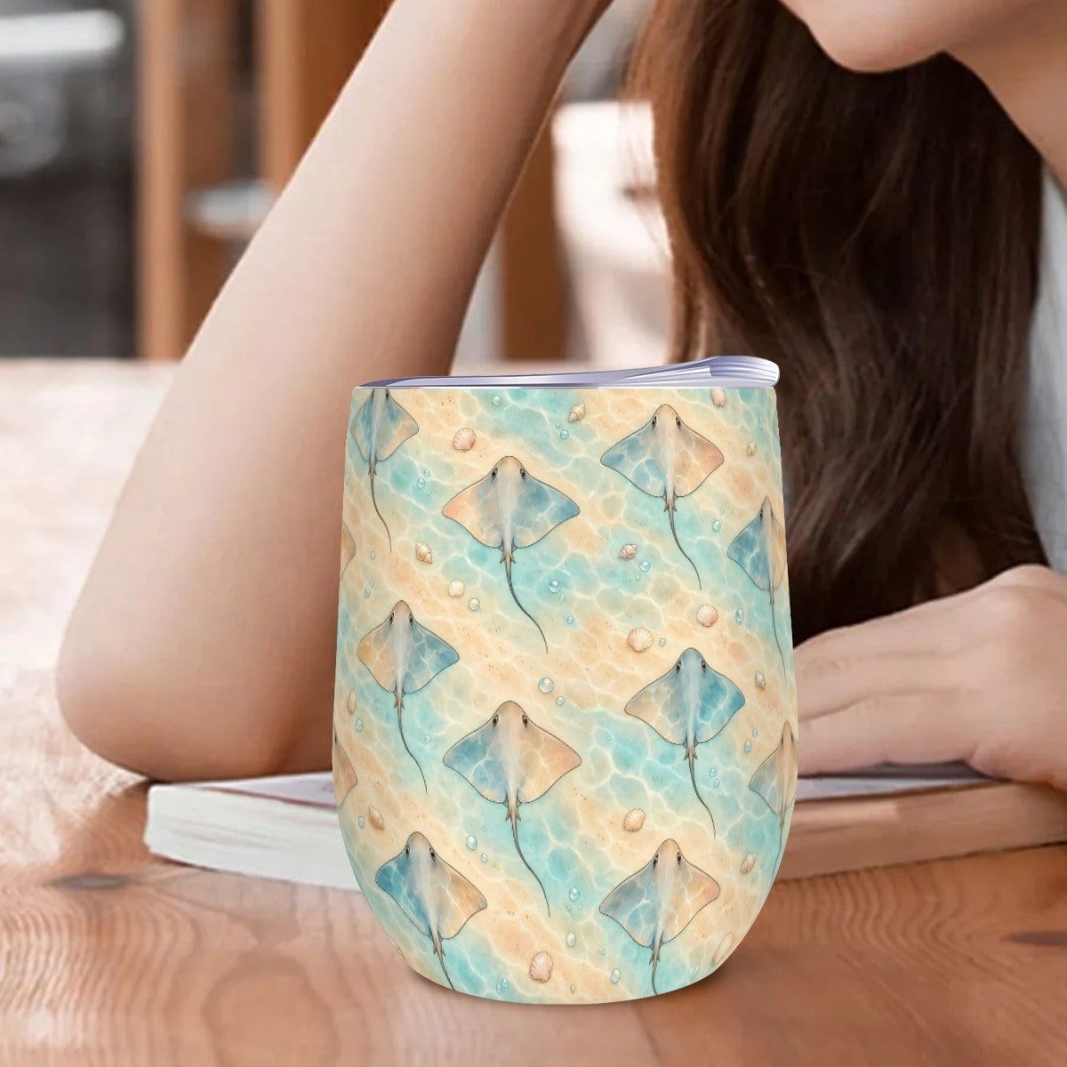 Stingray tumbler standing on a wooden table beside a woman resting her arm