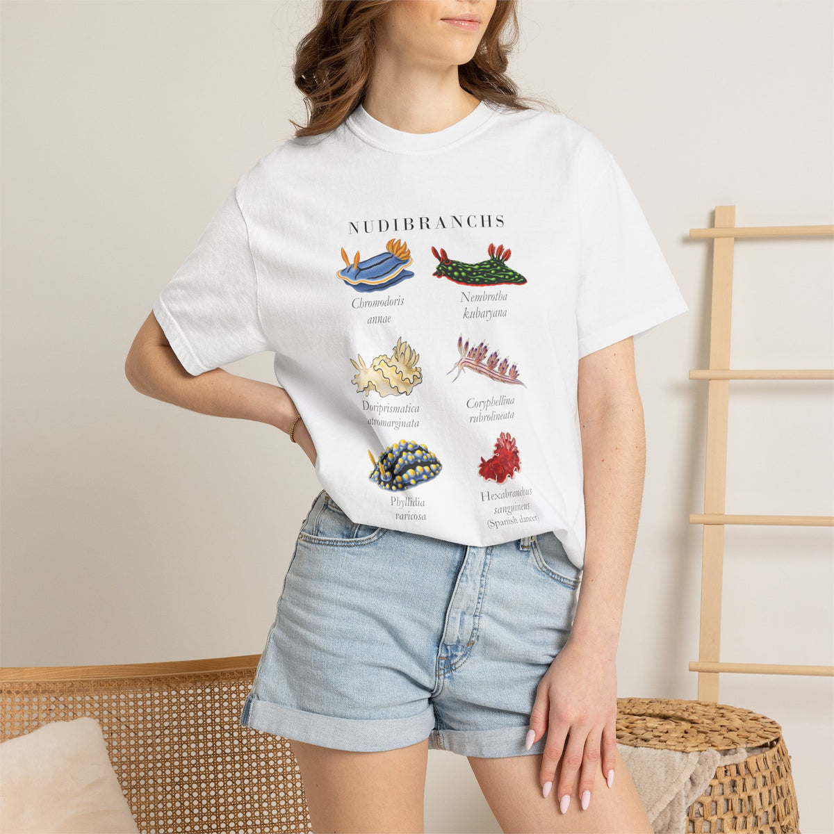 White nudibranch plate tee on a model with a hand on her hip, denim shorts, front view