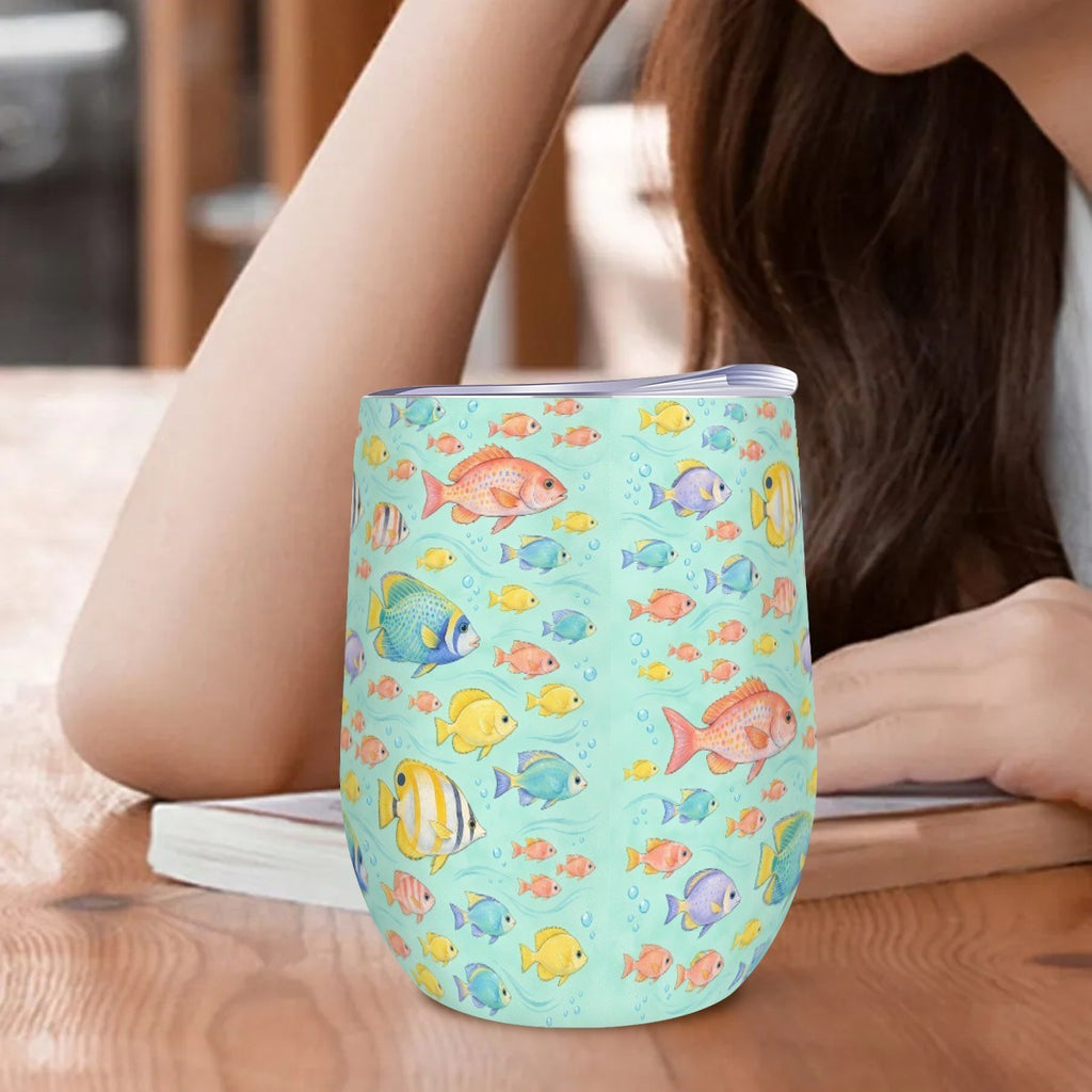 Reef fish tumbler standing on a wooden table beside a woman resting her arm