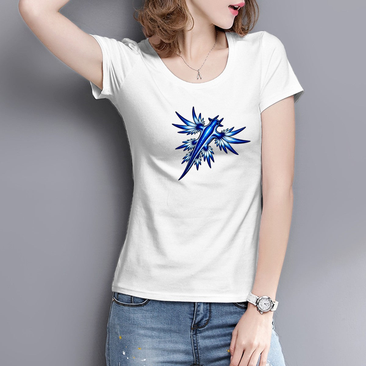 Woman in a white blue dragon sea slug tee against a grey wall