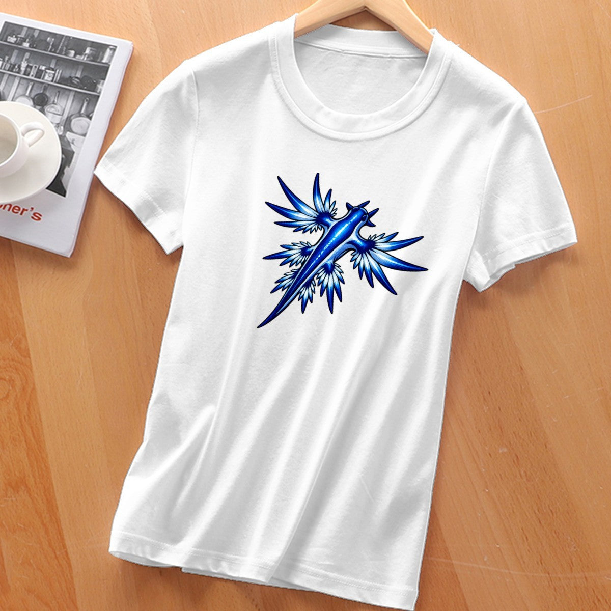 White blue dragon sea slug tee laid flat on a wooden table, front