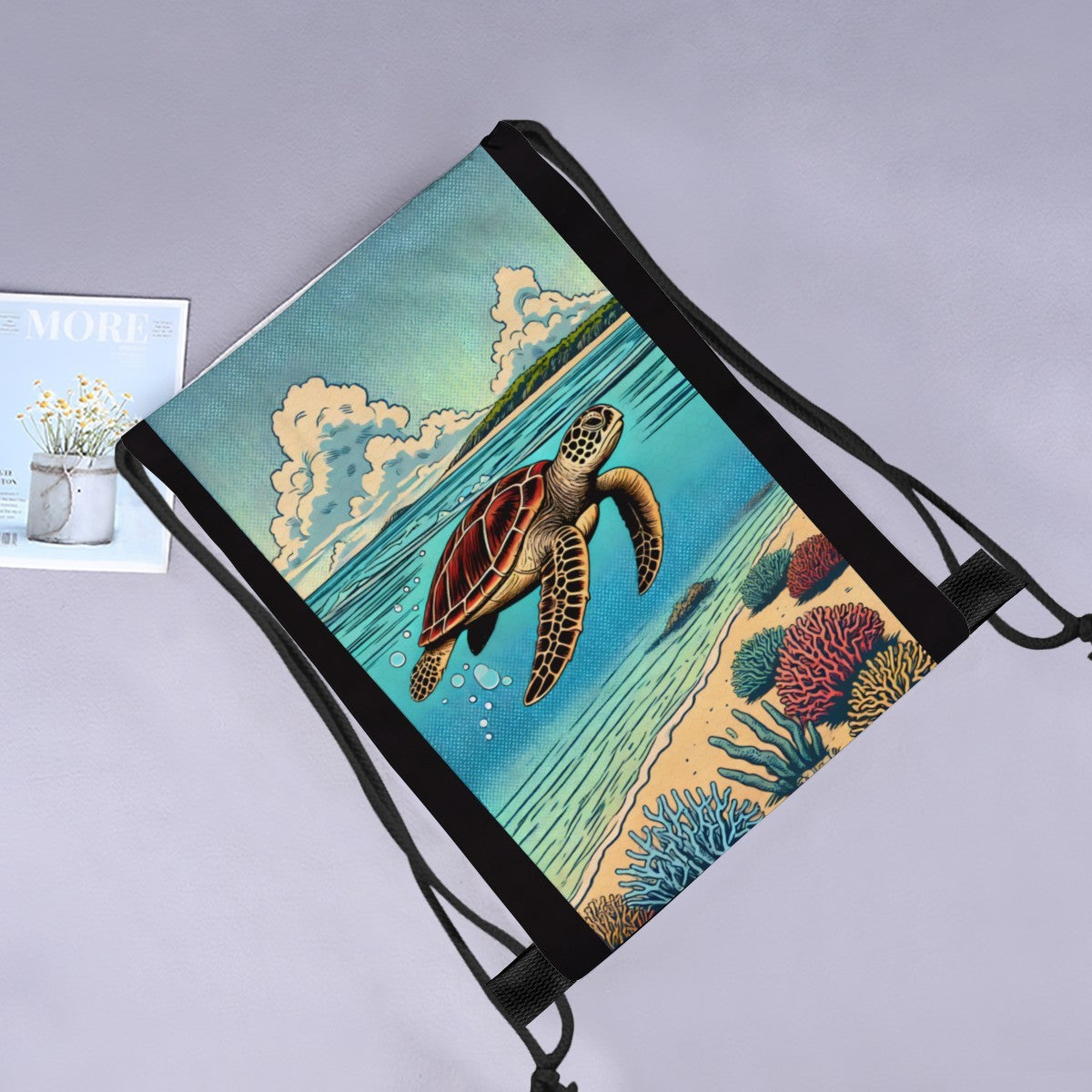 Turtle Cove drawstring bag laid flat next to a magazine and flowers.