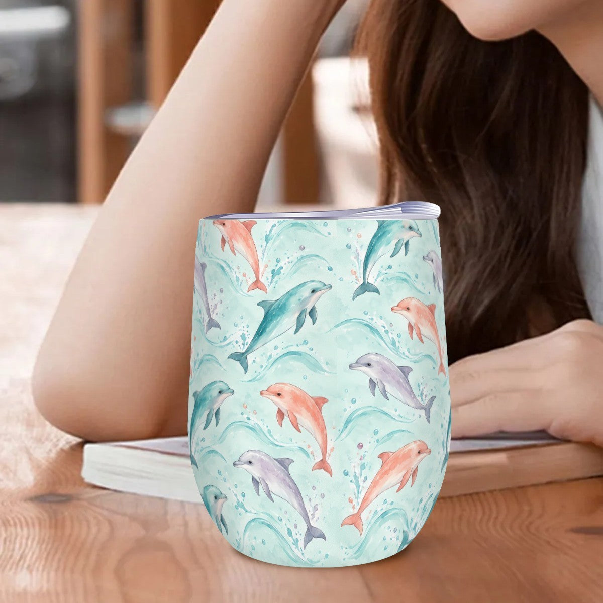 Dolphin tumbler standing on a wooden table beside a woman resting her arm