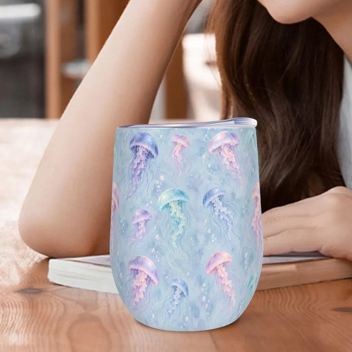 Jellyfish tumbler standing on a wooden table beside a woman resting her arm