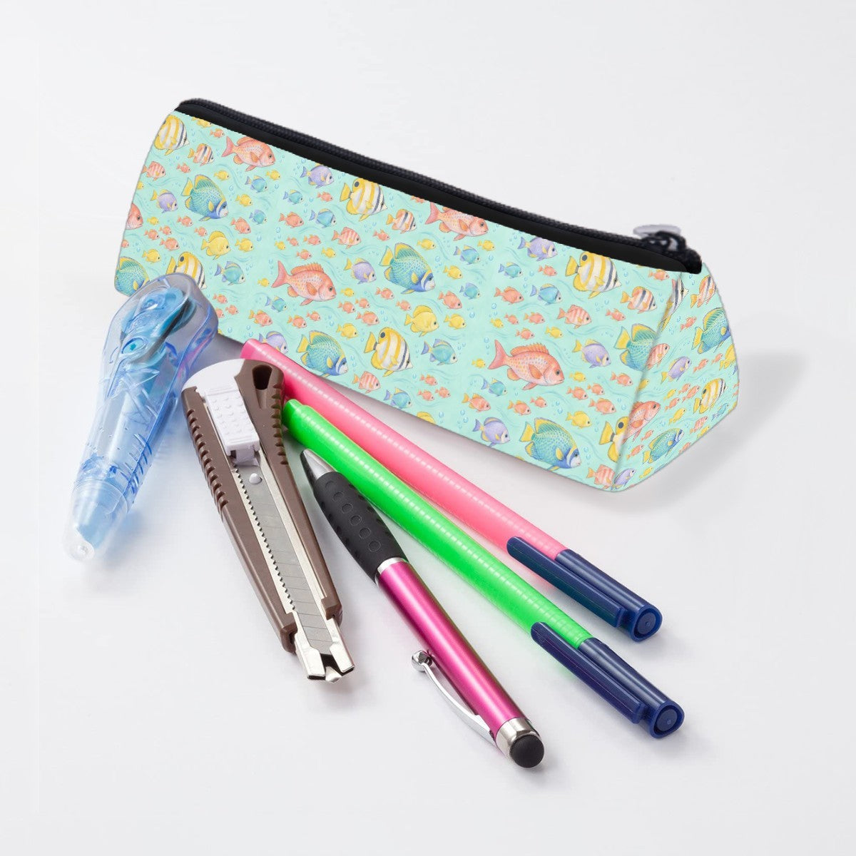 Reef fish pencil case lying beside pens and markers