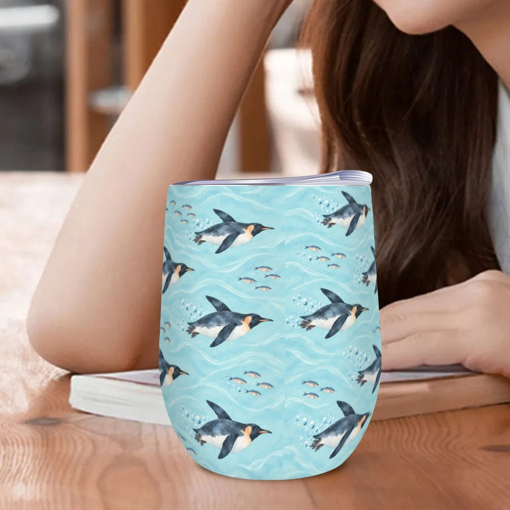 Penguin tumbler standing on a wooden table beside a woman resting her arm