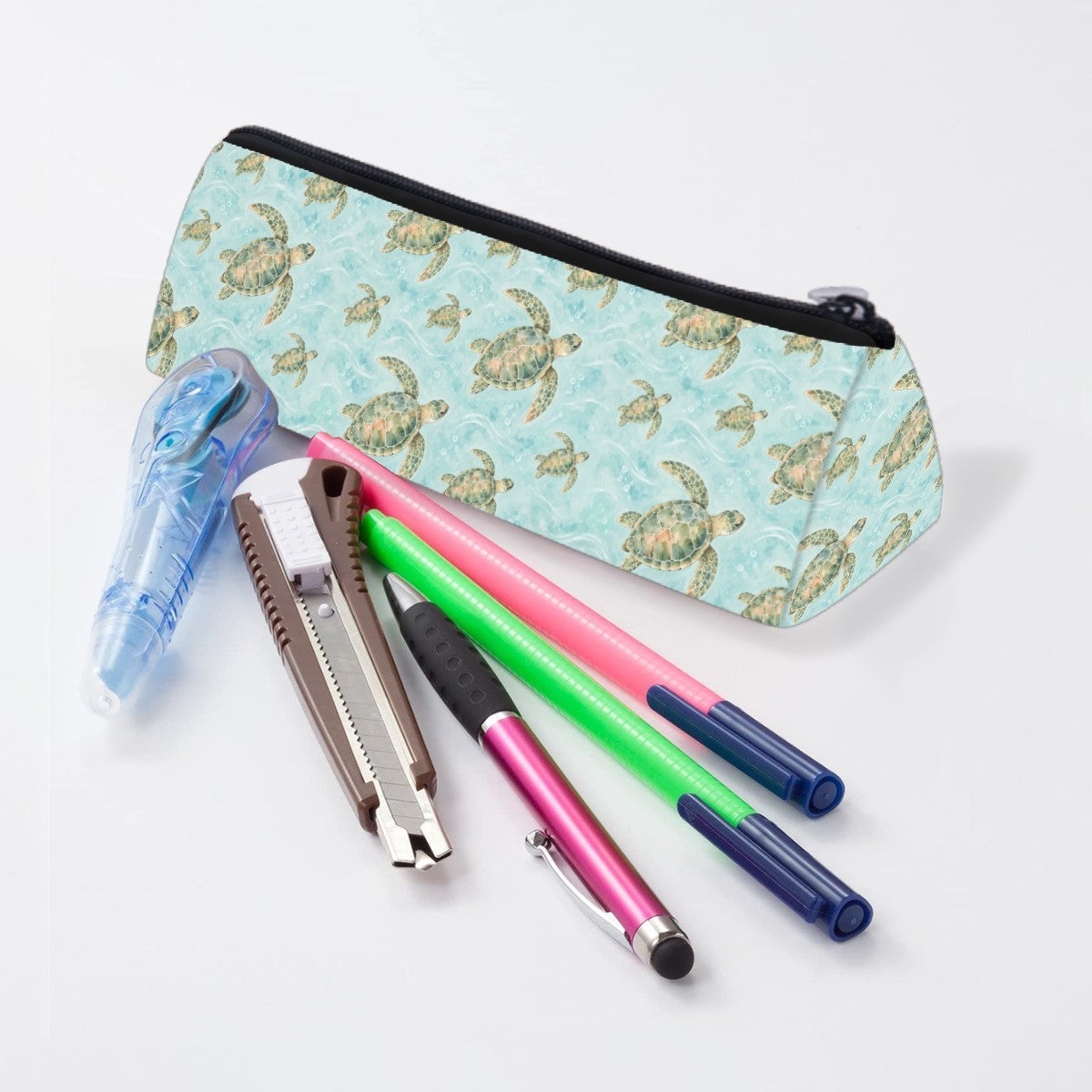 Sea turtle pencil case lying beside pens and markers