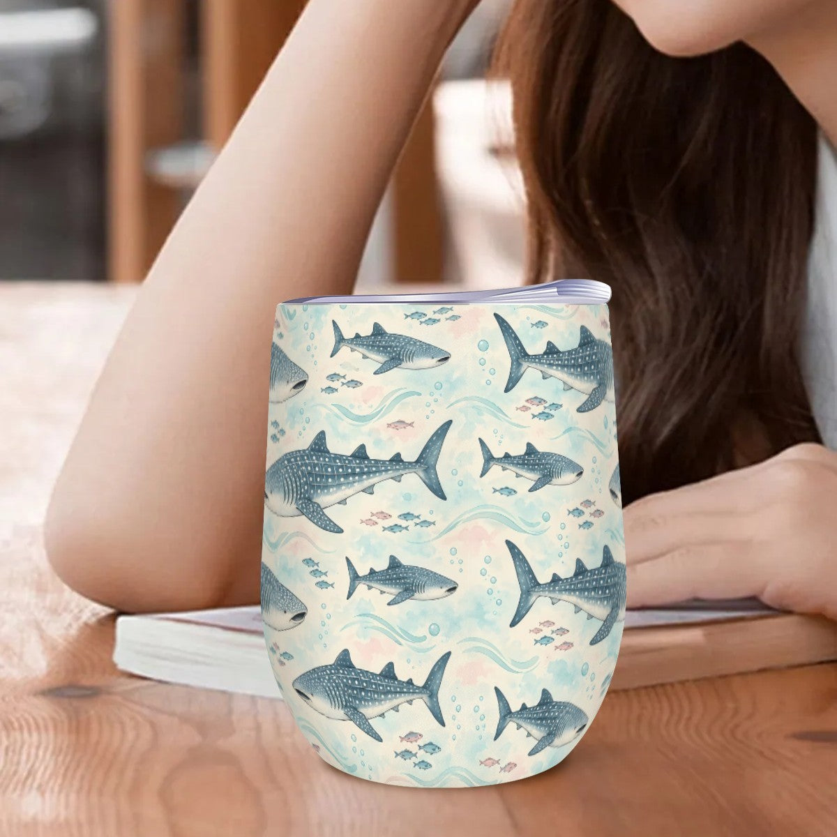 Whale shark tumbler standing on a wooden table beside a woman resting her arm