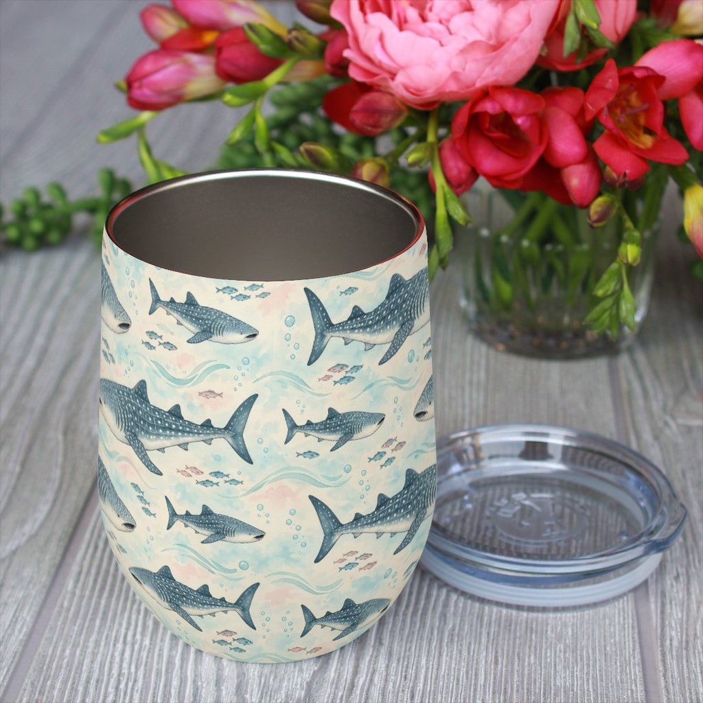 Whale shark pattern tumbler with its clear lid beside it on a wooden table, red flowers in the background