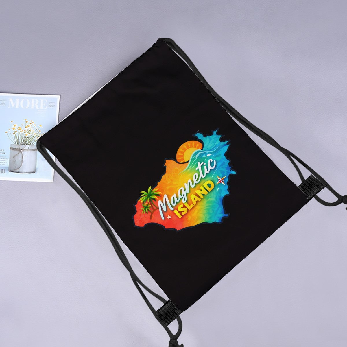 Magnetic Island Map drawstring bag laid flat next to a magazine and flowers.