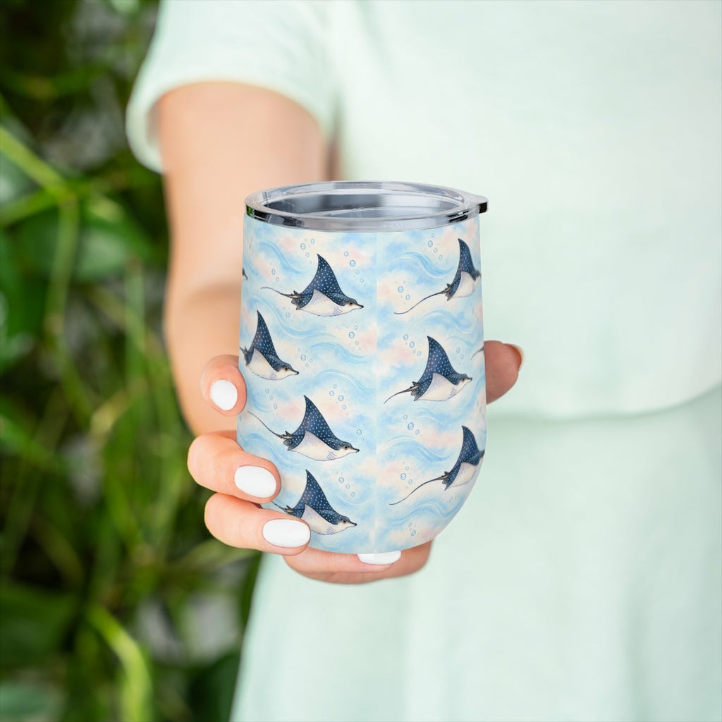 Hand holding the eagle ray pattern tumbler in front of green leaves, with a pale green top behind