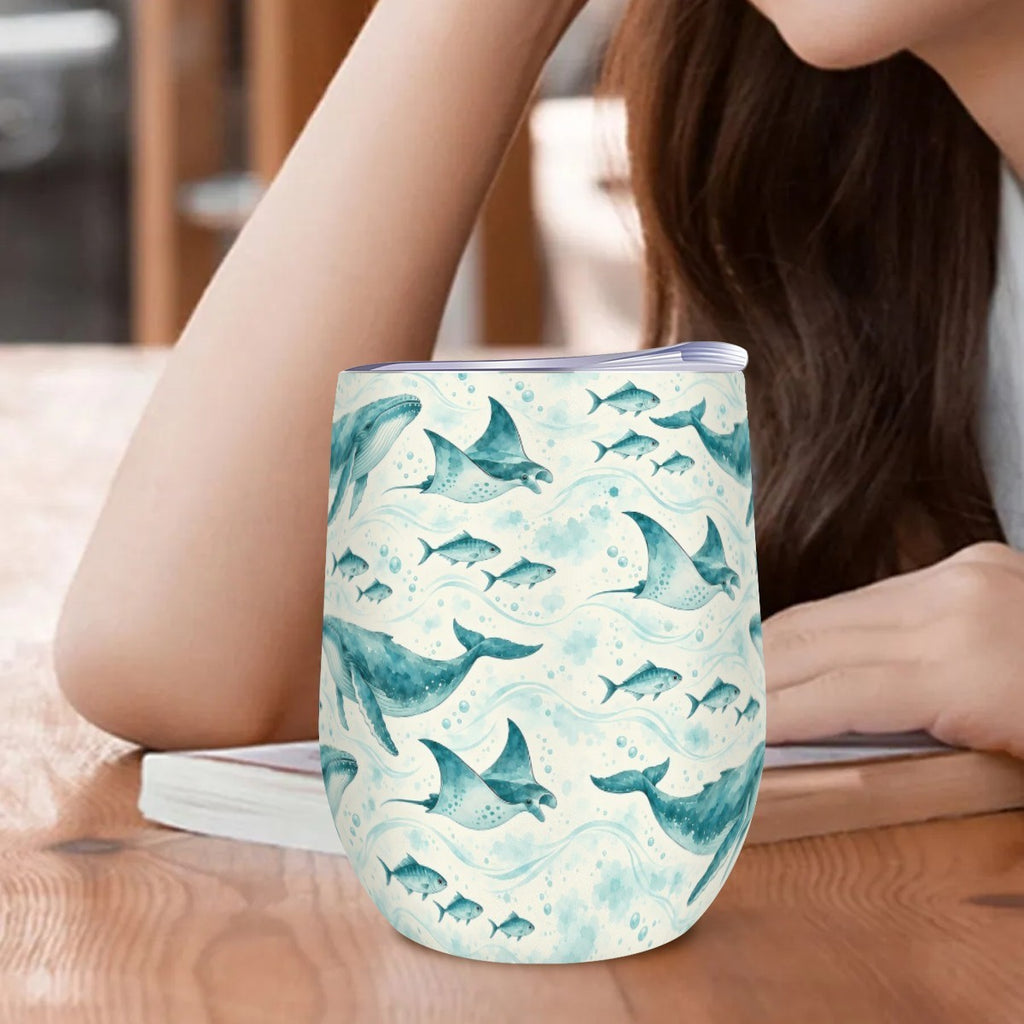 Whale and ray tumbler standing on a wooden table beside a woman resting her arm