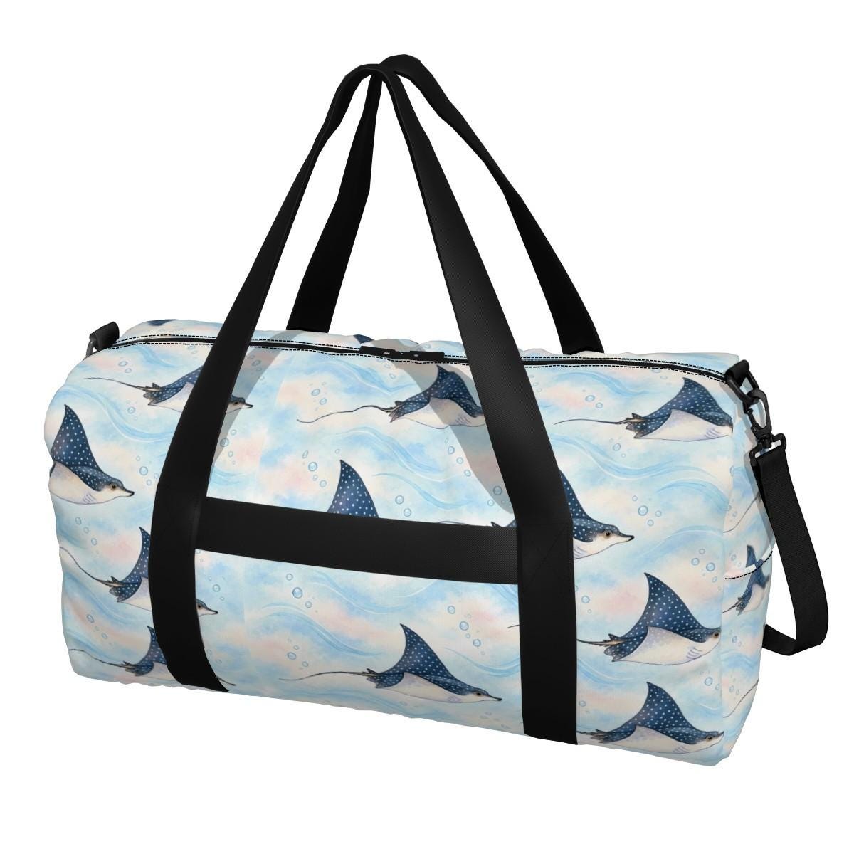 Front of the spotted eagle ray duffle bag showing rays on pale sky blue, with black carry handles